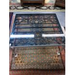 AN INTERESTING GLASS TOP COFFEE TABLE WITH METAL FRAME AND CAST IRON TRELLIS INSET