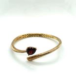 FEI LIU FINE JEWELLERY. A SILVER GILT HALLMARKED HINGED BANGLE SET WITH A PEAR CUT GARNET. WEIGHT