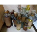 ELEVEN CLEAR GLASS CYLINDRICAL BOTTLES WITH SHORT NECKS AND DISC RIMS, MAINLY WITH CORK STOPPERS,