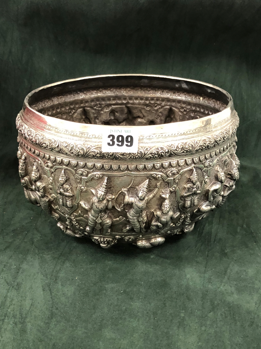 A BURMESE WHITE METAL BOWL, THE ROUNDED SIDES OF THE EXTERIOR RAISED WITH COURT SCENES OF FIGURES