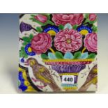 A PERSIAN CUERDA SECA TILE PAINTED WITH A BIRD FLANKING A VASE OF PINK FLOWERS. 20.5 x 20cms.