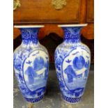 A PAIR OF JAPANESE BLUE AND WHITE BALUSTER VASES, EACH PAINTED WITH TWO RESERVES OF THREE FIGURES ON