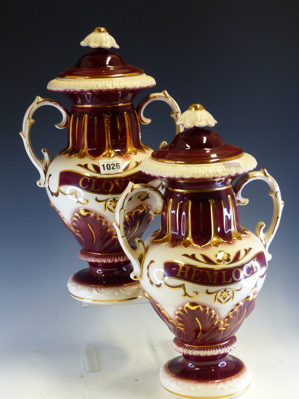 A PAIR OF POTTERY TWO HANDLED BALUSTER JARS AND COVERS LABELLED HEMLOCK AND CLOVES IN GILT ON A WINE - Image 2 of 4