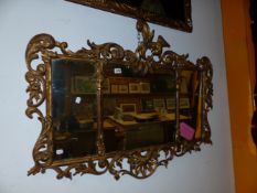 A TRIPLE PLATE MIRROR WITHIN A CARVED GILTWOOD FRAME PIERCED WITH FOLIAGE ABOUT ROCAILLE, THE SI