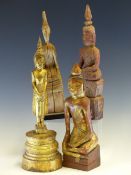 FOUR LAO CARVED WOOD BUDDHAS, THREE SEATED AND THE TALLEST GILT AND STANDING. H 33cms.