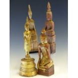 FOUR LAO CARVED WOOD BUDDHAS, THREE SEATED AND THE TALLEST GILT AND STANDING. H 33cms.