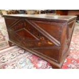 AN EARLY OAK COFFER, THE FRONT INLAID WITH A DIAMOND SHAPED BAND OF FLOWERS AND FOLIAGE ABOVE THE