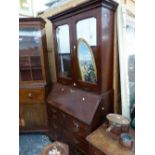 A GEORGE III MAHOGANY BUREAU BOOK CASE WITH A CAVETTO CORNICE ABOVE MIRRORED DOORS AND TWO CANDLE