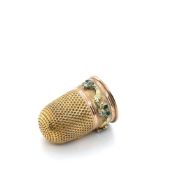 AN ANTIQUE THIMBLE SET WITH OLD CUT DIAMONDS AND EMERALDS AMONGST A FOLIATE SCROLL BORDER.