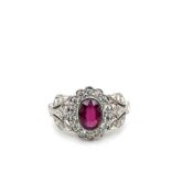 A PLATINUM HALLMARKED RUBY AND DIAMOND CLUSTER RING WITH DIAMOND SET FOLIATE STYLE SHOULDERS. FINGER