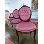 A PAIR OF VICTORIAN MAHOGANY SIDE CHAIRS WITH FLOWER CRESTED BUTTON UPHOLSTERED OVAL BACKS, THE