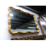 A 20th C. ITALIAN MIRROR IN A GILT WAVY RECTANGULAR FRAME CORNERED BY TREFOILS. 85 x 120cms.