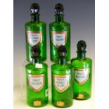FIVE GREEN GLASS PHARMACY BOTTLES AND STOPPERS, EACH GILT WITH THE ROYAL ARMS BELOW SHIELD SHAPED