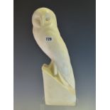 A WHITE COMPOSITION FIGURE OF AN OWL LOOKING TO ONE SIDE AS IT PERCHES ON A LEDGE. H 39cms.