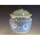 A CHINESE BLUE AND WHITE ROUNDED CYLINDRICAL JAR AND COVER PAINTED WITH LOTUS AND SCROLLED BARBED