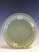A CHINESE LONGQUAN CELADON DISH, THE FLUTED CAVETTO INCISED WITH FLOWERS WITHIN THE BARBED RIM. Dia.