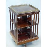 AN EDWARDIAN MAHOGANY ROTARY BOOKCASE WITH A BRASS GALLERIED TOP, THE QUADRIPARTITE PLINTH ON