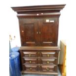 AN EARLY OAK LINEN PRESS, AN OVOLO FRONTED DRAWER ABOVE THE DOORS TO THE UPPER HALF, THE BASE WITH