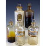 FIVE CLEAR GLASS PHARMACY BOTTLES AND STOPPERS, TWO WITH RECESSED LABELLING: OL: EUCALYPT: AND ACID.