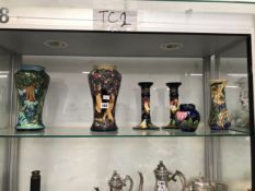 A PAIR OF MOORCROFT CANDLESTICKS, THREE VASES AND A COVERED JAR