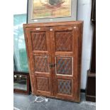 AN INDONESIAN PINECABINET THE SIDES RECESSED BEHIND THE TWO DOORS,EACH WITH THREE DIAMOND DICED PA