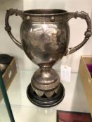 A TWO HANDLED BALUSTER TROPHY CUP AND SHIELD MOUNTED WOOD STAND BY WAKELEY AND WHEELER, DUBLIN 1927,