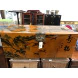 A CHINESE AMBER GROUND LACQUER TRUNK PAINTED WITH A HUNT AND A VILLAGE SCENE. W 105 x D 47 x H