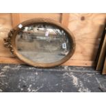 A DECORATIVE OVAL GILT MIRROR