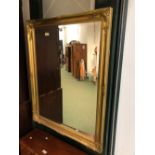 A DECORATIVE GILT BEVELLED EDGE MIRROR. 114 x 90cms