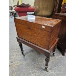 A EARLY 19th CENTURY PLUM PUDDING MAHOGANY CELLARETTE ON STAND, THE RECTANGULAR HINGED LID OVER
