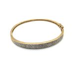 A DIAMOND HINGED BANGLE. UNHALLMARKED, ASSESSED AS 9ct GOLD. WEIGHT 11.38grms.