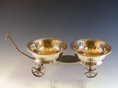 AN ANTIQUE WINE CADDY WITH A PAIR OF SILVER WINE COASTERS ON A FOUR WHEELED TROLLEY BY C P,