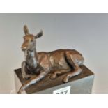 A 20th C. BRONZE FIGURE OF A RECUMBENT DOE ON A BLACK STONE BASE. W 13.5cms.