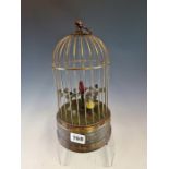 A TWO BIRD AUTOMATON, THE RED AND YELLOW BIRDS AMONGST FOLIAGE IN THEIR CAGE. H 28cms.