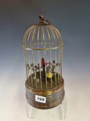 A TWO BIRD AUTOMATON, THE RED AND YELLOW BIRDS AMONGST FOLIAGE IN THEIR CAGE. H 28cms.