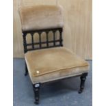 AN ARTS AND CRAFTS EBONISED NURSING CHAIR, THE UPHOLSTERED TOP RAIL ABOVE AN OPEN ARCHED BALUSTRADE,