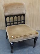 AN ARTS AND CRAFTS EBONISED NURSING CHAIR, THE UPHOLSTERED TOP RAIL ABOVE AN OPEN ARCHED BALUSTRADE,