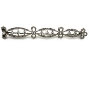 AN ANTIQUE DIAMOND BAR BROOCH. SET WITH TWELVE RUBOVER SET CENTRAL STONES RIBBON FRAMED WITH DIAMOND