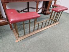 A BRASS CLUB FENDER, THE RED LEATHERETTE SEATS TO EACH END SUPPORTED ON BARS OF SQUARE SECTION. W