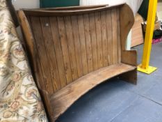 A ANTIQUE PINE SETTLE, THE CURVED PLANK BACK JOINED BY A HOOD TOP, THE WING TOPPED SIDES CURVING