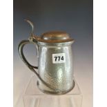 A TUDRIC PEWTER PINT TANKARD,THE HINGED LID AND BELLIED BODY WITH HAMMERED DECORATION