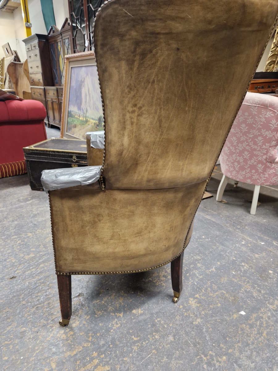 AN ANTIQUE LEATHER UPHOLSTERED WING ARMCHAIR WITH THE BACK ROUNDING OVER THE ARMS, THE SQUARE - Image 4 of 5