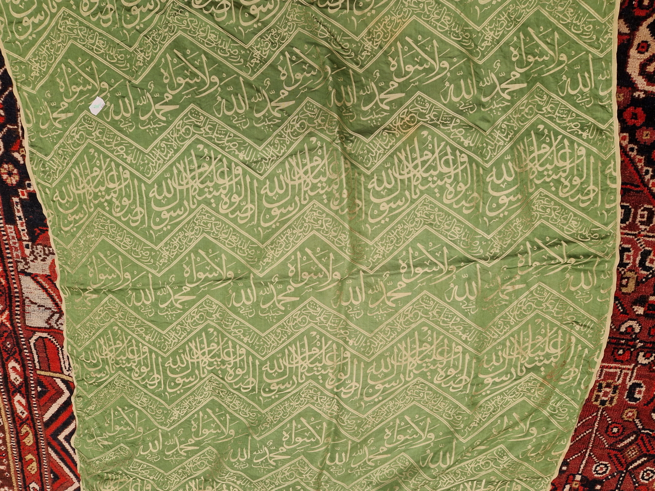 AN ISLAMIC GREEN SILK PANEL WOVEN IN SILVERY GREY WITH CHEVRON BANDS OF SCRIPT. 148 x 84cms. - Image 4 of 6