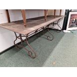 A RECTANGULAR WEATHERED STEEL REFECTORY TABLE, THE WROUGHT IRON LEGS TO EACH NARROW END ON PAIRS OF