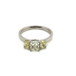 A HALLMARKED PLATINUM, WHITE AND YELLOW DIAMOND THREE STONE RING. THE CENTRAL WHITE DIAMOND