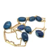 A CONTINUOUS STAND OF BLUE HARD STONE BEADS WITH BAR AND LINK CHAIN. LENGTH APPROX 70cms,