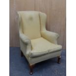 A GEORGIAN STYLE WING ARMCHAIR UPHOLSTERED IN YELLOW GROUND MATERIAL ABOVE WALNUT CABRIOLE FRONT