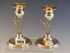 A PAIR OF 925 SILVER CANDLESTICKS, THE S-SCROLL STEMS EACH WITH A CHILD STANDING TO ONE SIDE,