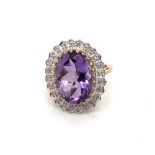 A HALLMARKED 9ct GOLD AMETHYST AND DIAMOND OVAL CLUSTER RING. FINGER SIZE I. WEIGHT 4.55grms.