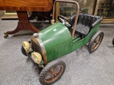 A GREEN PAINTED PEDAL CAR WITH THE NUMBER PLATE 1939 BELOW TWO HEAD LIGHTS, THE CUSHIONED SEAT IN